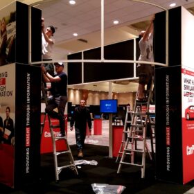 Technicians installing flexible fabric graphics on tradeshow display frame