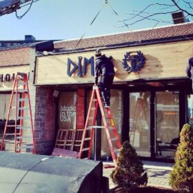 Dimi's Wood Custom Fascia Signage being installed by technicians on ladders