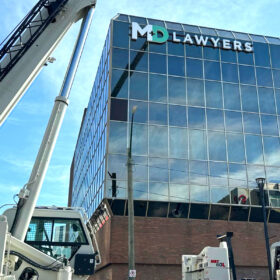MD Lawyers channel letter sign installed on top of commercial building using crane