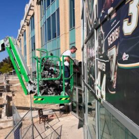 Technician Installing window graphics at Canada Life Centre