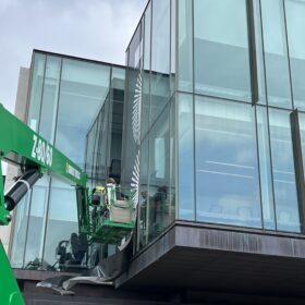 Technicians using aerial lift to install window graphics at Ivey