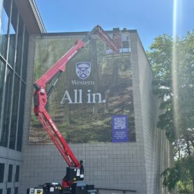 Installers using aerial lift to install large format vertical banners at Western University