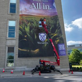 Large format vertical banners being installed by technicians for Western University